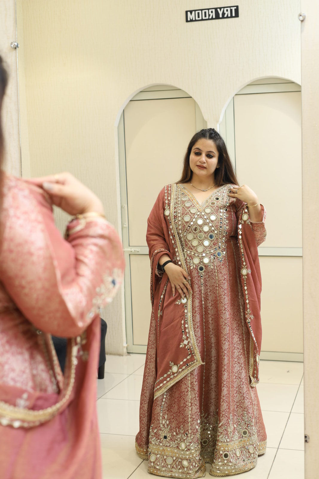 Woman in a pink Indian outfit with mirror work in a fitting room
