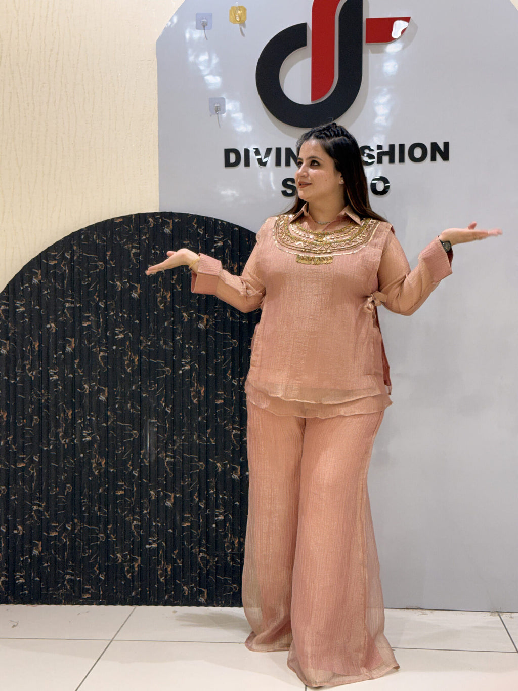 Woman in peach floral embroidered co-ord set gesturing