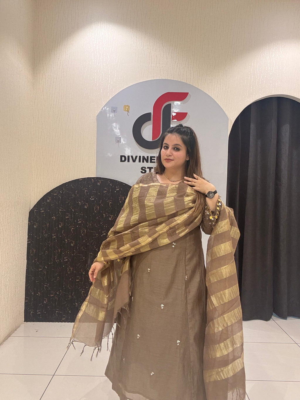 Sophisticated brown Mul suit featuring delicate embroidery and a golden striped dupatta