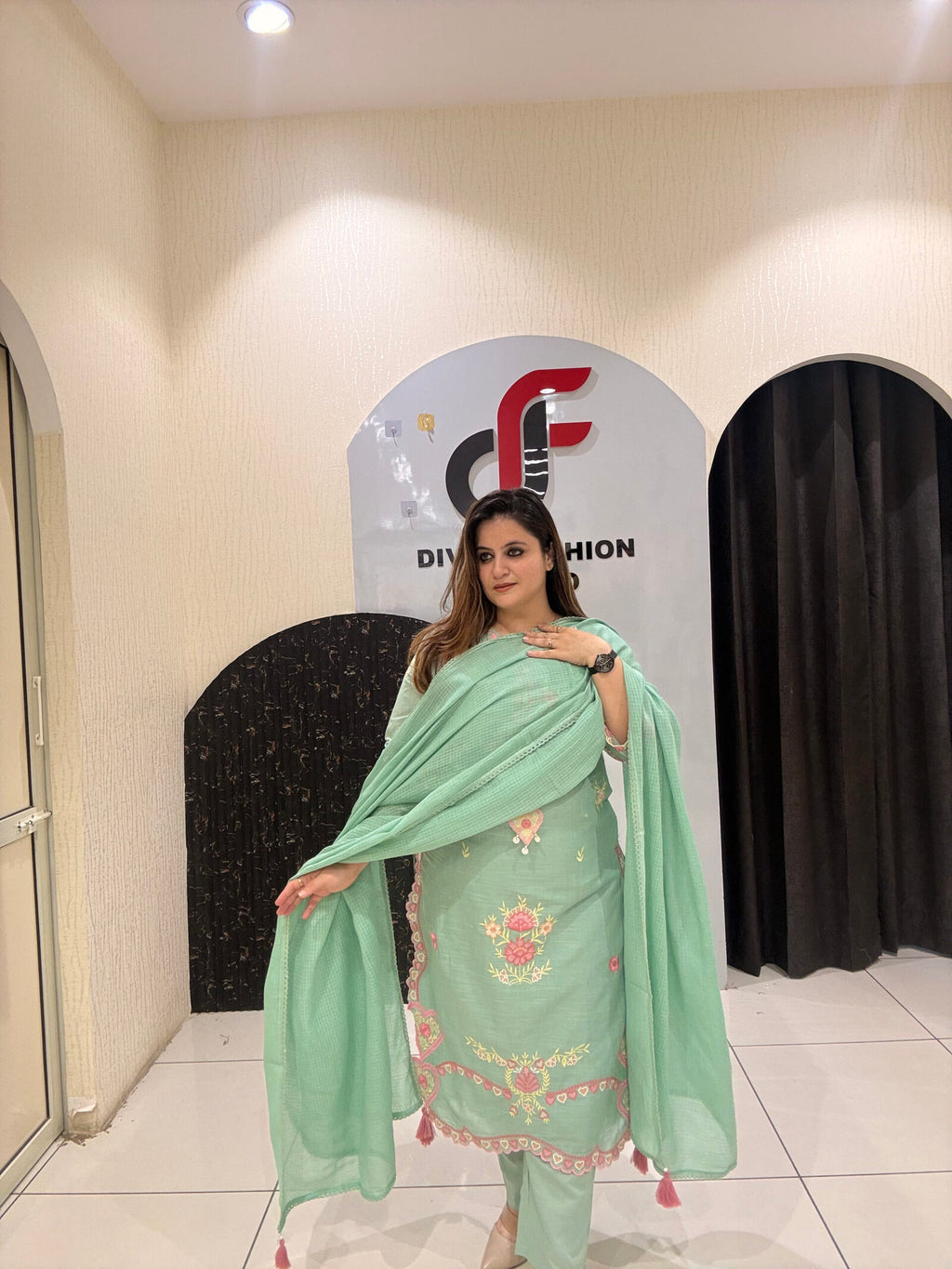 Graceful mint green cotton suit featuring intricate floral embroidery and tassel detailing.