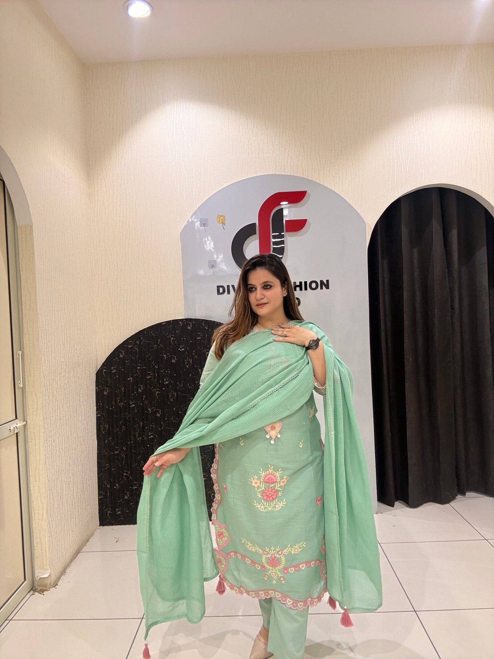 Graceful mint green cotton suit featuring intricate floral embroidery and tassel detailing.