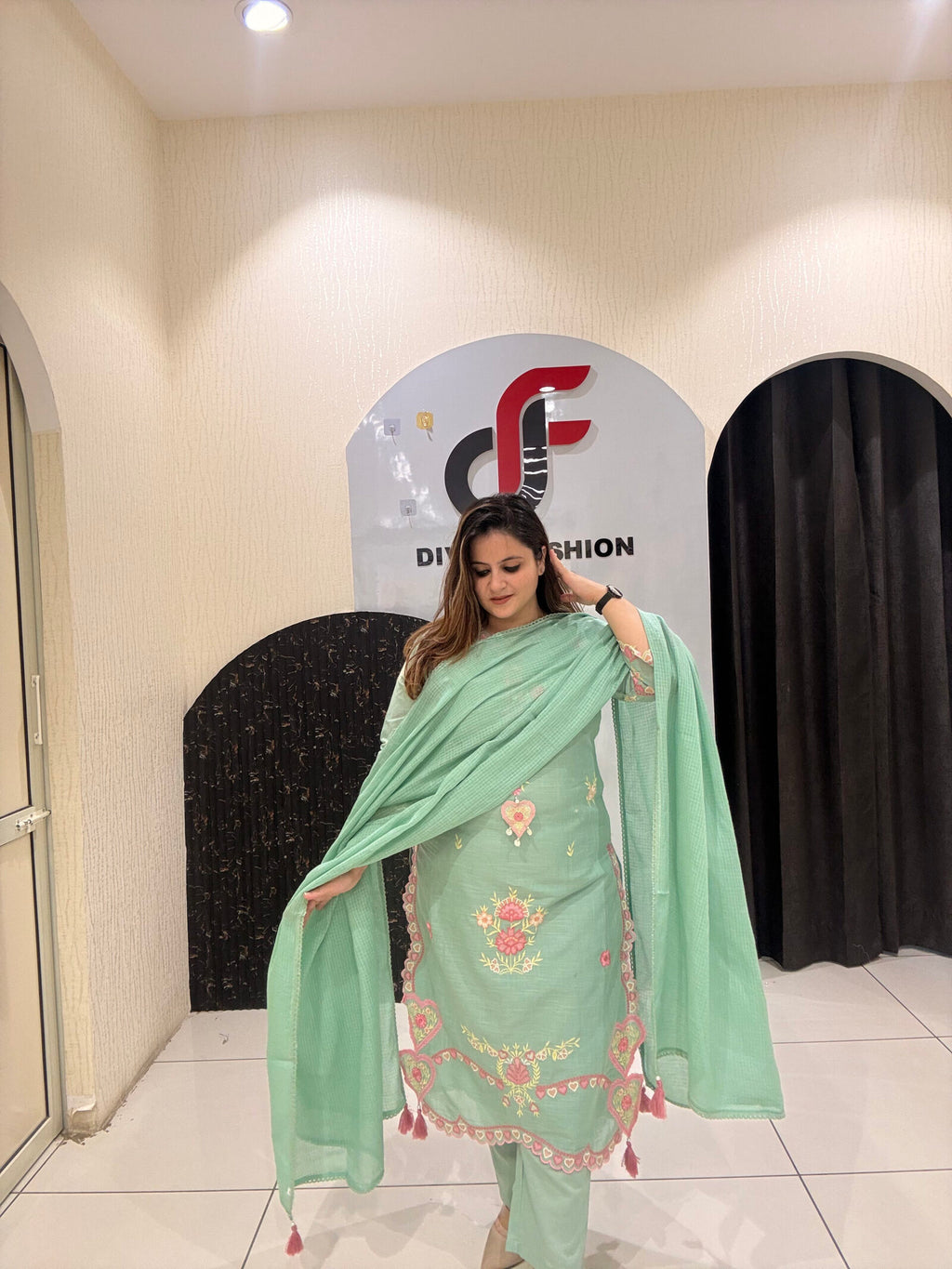 Graceful mint green cotton suit featuring intricate floral embroidery and tassel detailing.