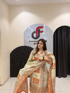 Graceful cream and orange partywear suit featuring intricate ethnic prints and a matching dupatta with tassel detailing.