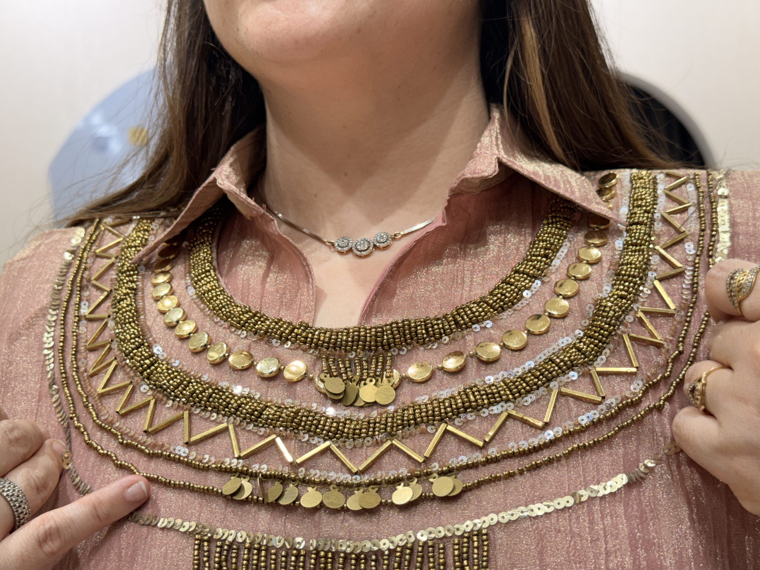 Close-up of a woman wearing a pink floral embroidered button-down co-ord set with intricate gold beadwork and sequins.