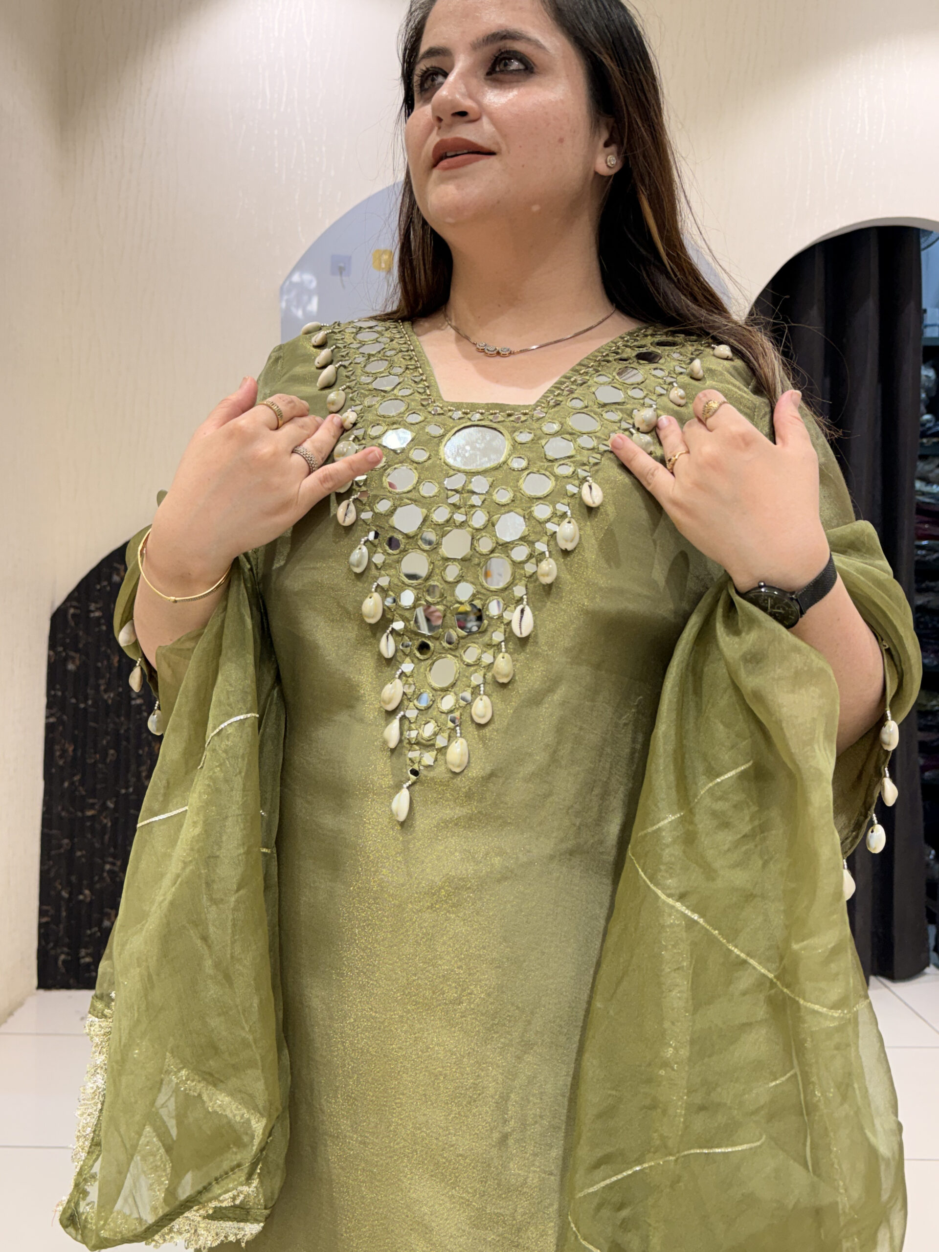Woman in a green, embellished kaftan with shell details
