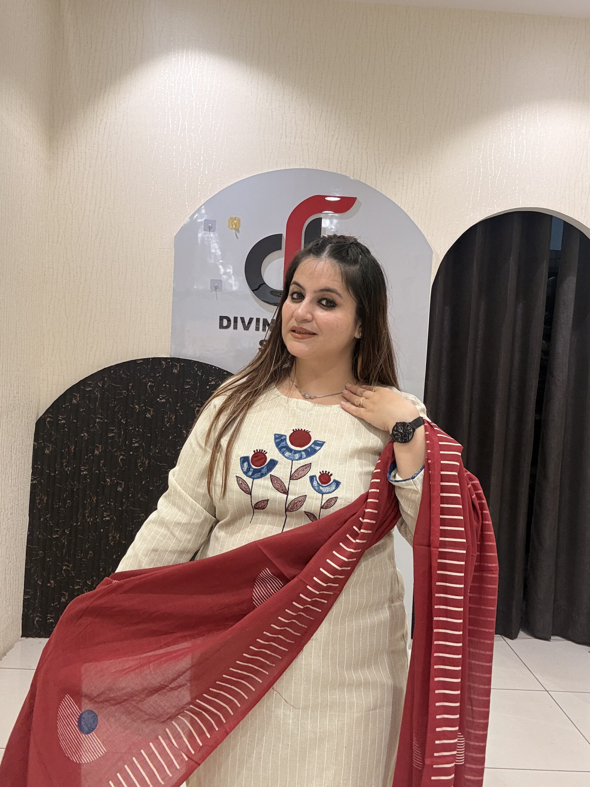 Elegant cream cotton suit featuring floral embroidery in red and blue tones, paired with a contrasting red dupatta.