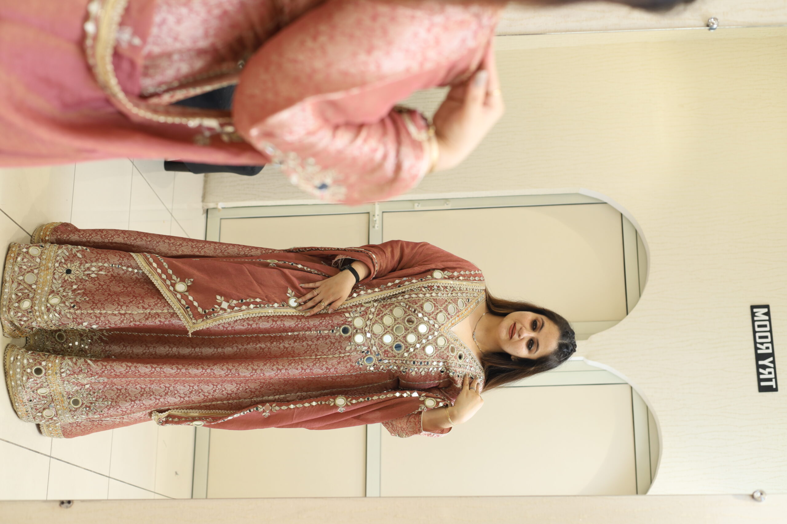 Woman in a pink Indian outfit with mirror work in a fitting room